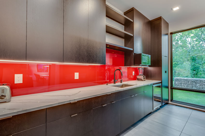 Kitchen with red backsplash as accent wall, wood cabinets, and countertop
