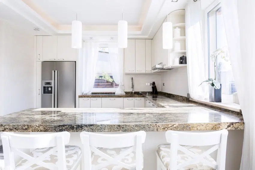 Kitchen with sealed granite countertop, chairs, hanging lights, and window