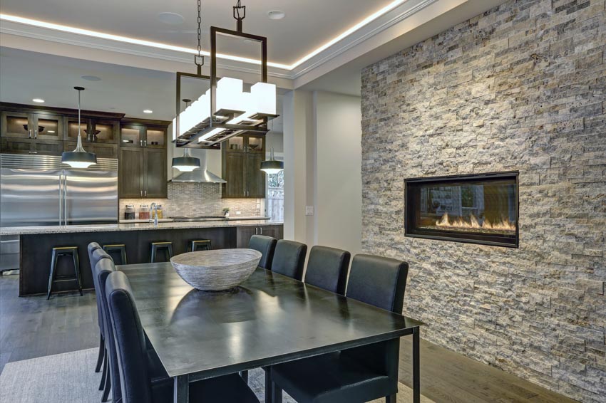 Kitchen with stone accent wall, fireplace, table, chairs, hanging lights, and center island