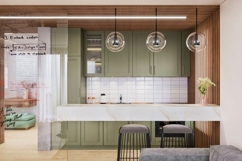 Kitchen with wet bar backsplash, hanging lights, and green cabinets