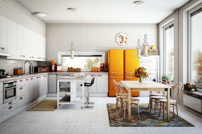 Kitchen with white tile accent wall, cabinets, counter, orange refrigerator, and windows