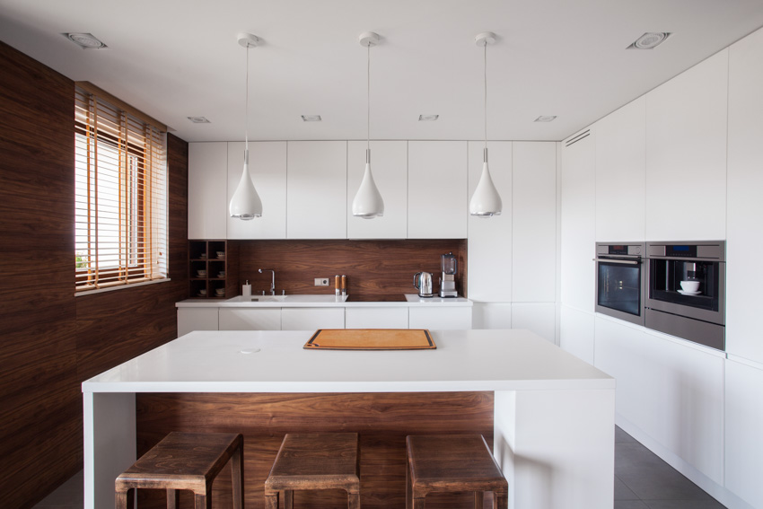 Kitchen with wood accent wall, center island, pendant lights, and white cabinets