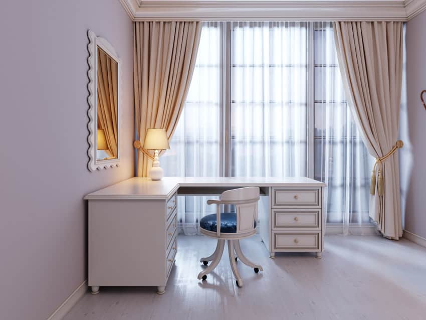L-shaped desk in a room with window, curtains, mirror, and lamp