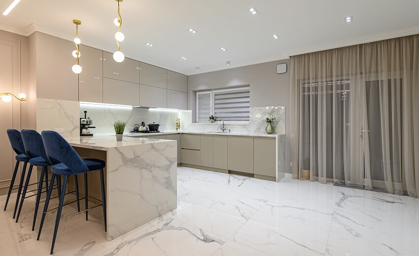 Large modern white marble kitchen with stylish lighting fixtures and floor-to-ceiling sheer curtains