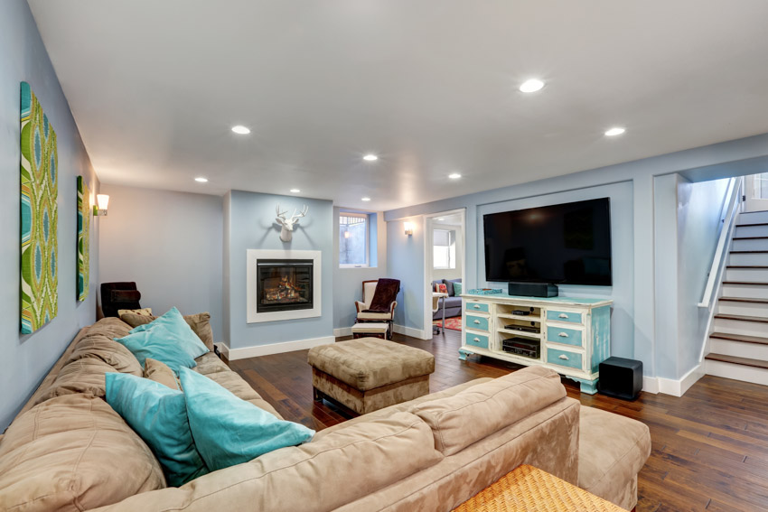 Living room in basement with couches, stairway, light blue walls, television, and wood flooring