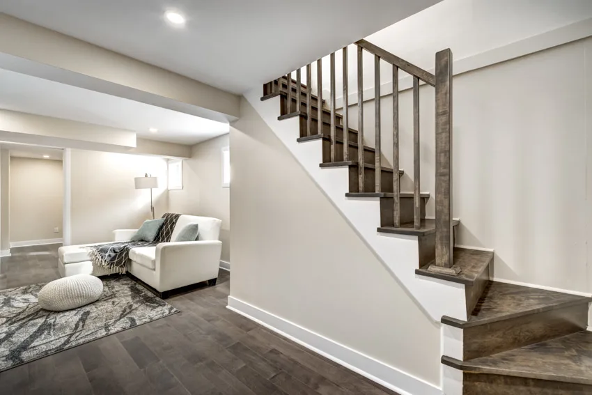 Basement with wooden staircase, couch, chaise lounge and area rug