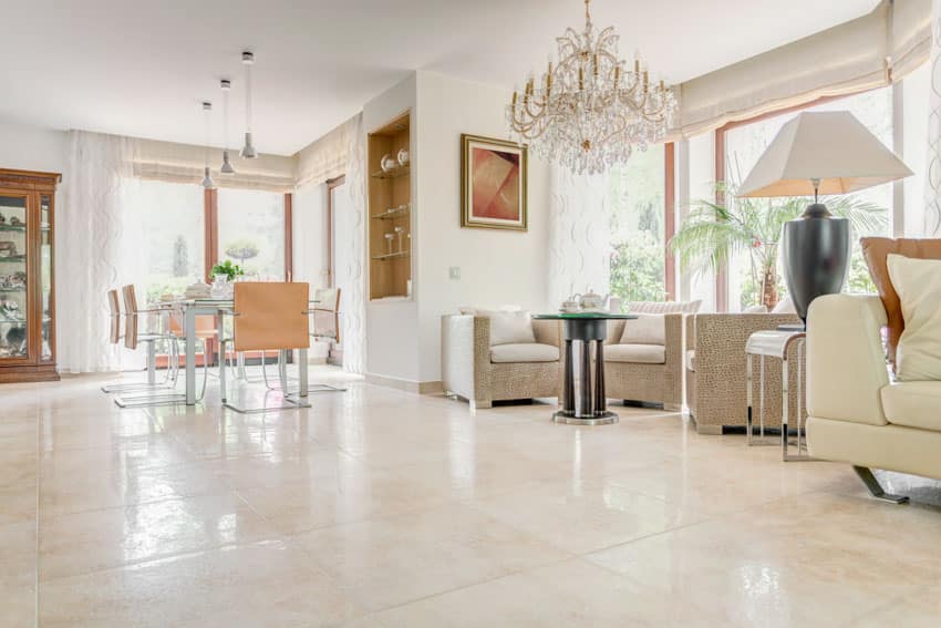 Living room with porcelain floor tiles, couches, chandelier, chairs, windows, and glass door