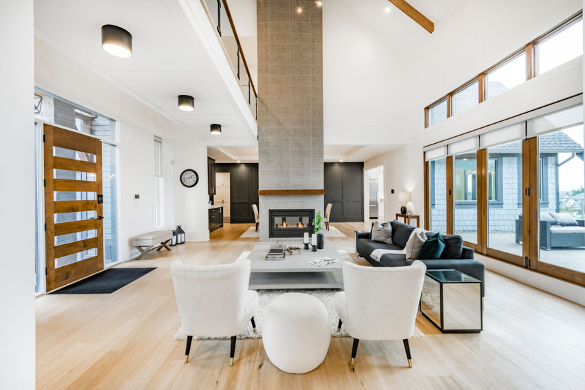 Living room with floor to ceiling fireplace, chairs, wood flooring, and ceiling lights