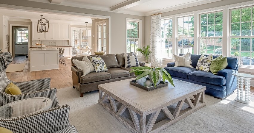 Living room with a loveseat, leather sofa, wood coffee table patterned armchairs and windows