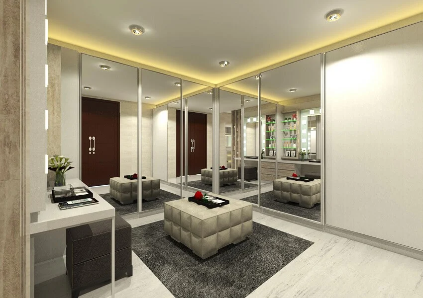 Luxurious walk-in closet with full length mirror sliding doors and ottoman on grey carpet