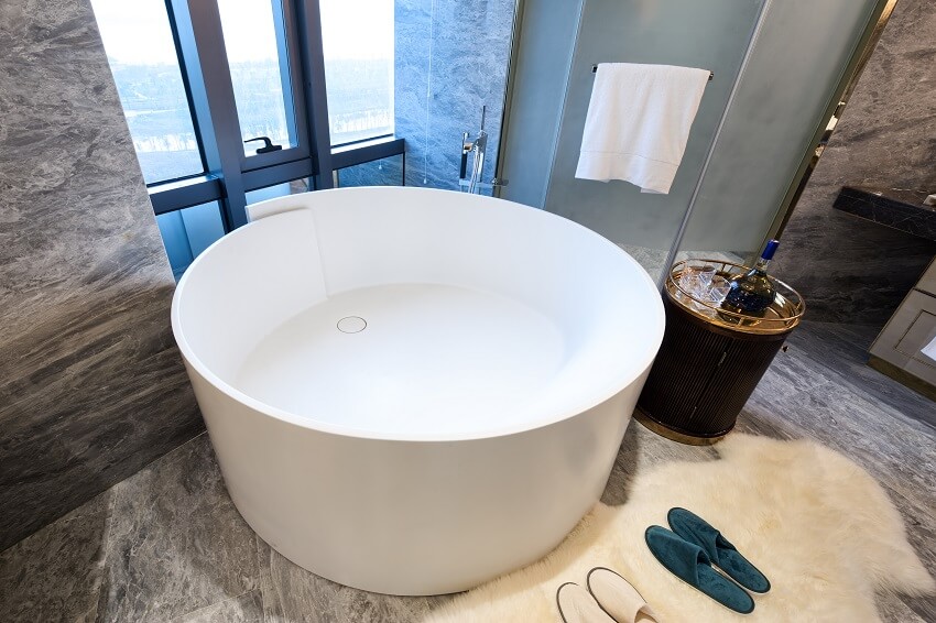 Luxury bathroom with Japanese style tub, fur rug, and marble tile wall and floor