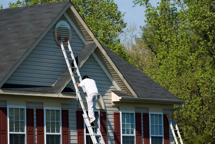 Man climbing up to roof using ladder