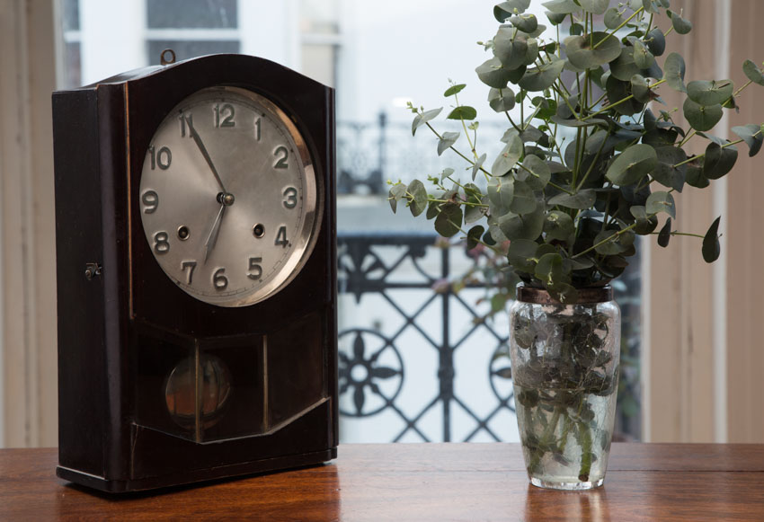 Miniature grandfather clock on table and indoor plant