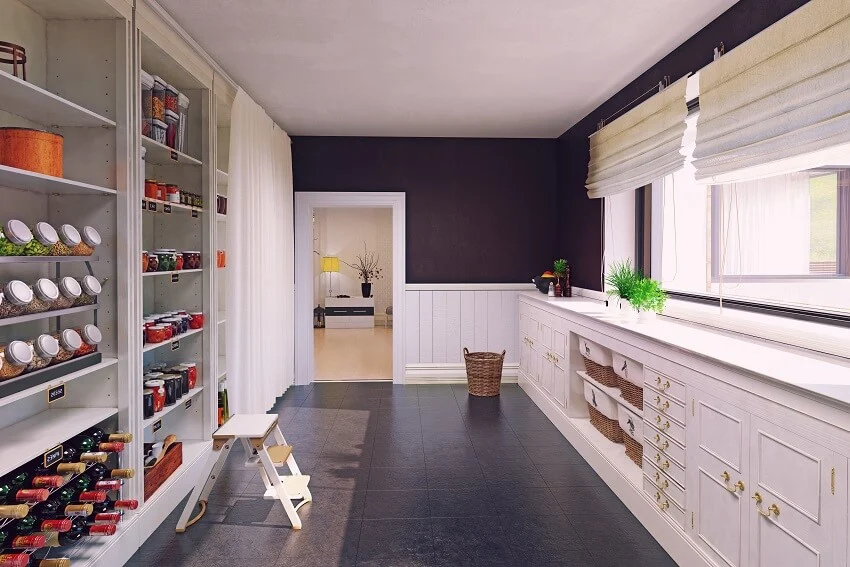 Modern butlers pantry interior with black tile floor, large windows with shade, and white cabinets and storage