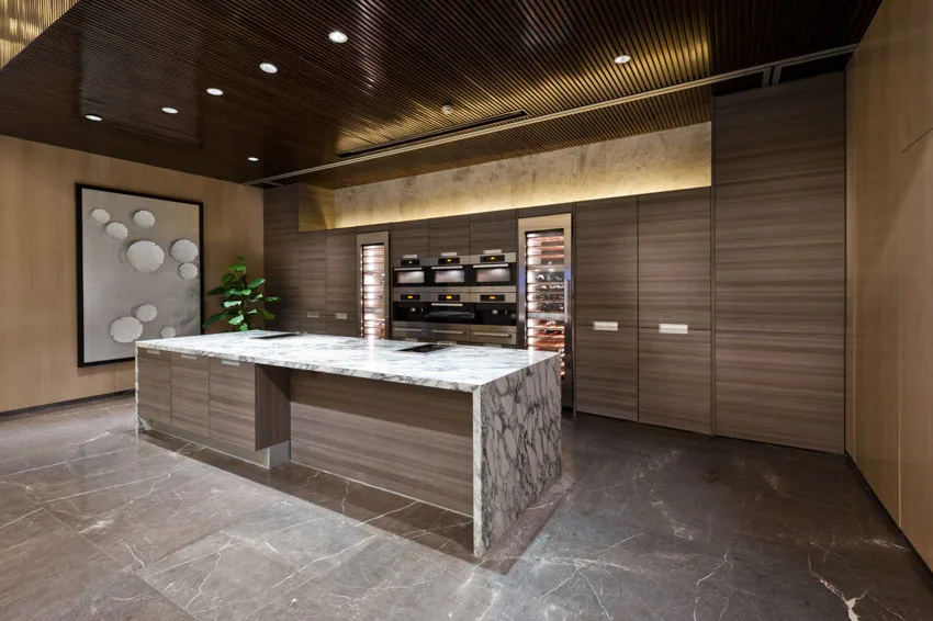 Modern kitchen with illuminated translucent stone surface countertop, center island, wood cabinets, and tile floor
