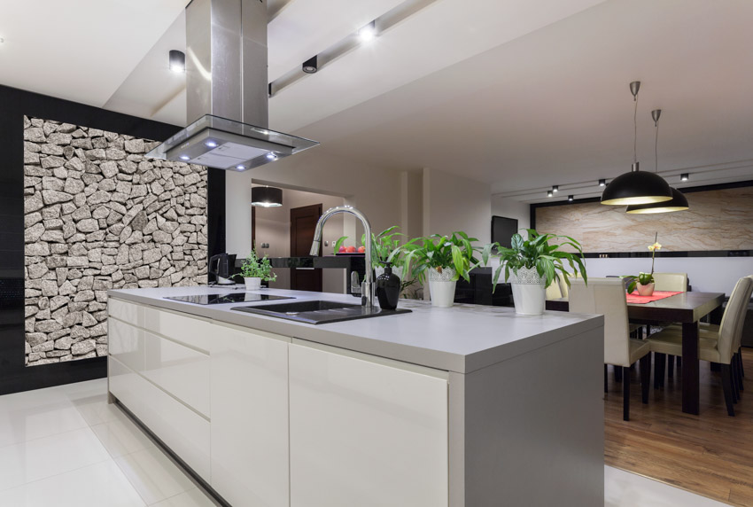 Modern kitchen with stone accent wall, center island, drawers, countertop, and range hood