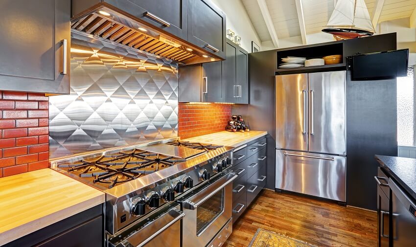Modern kitchen with under cabinet lighting, hardwood floor, and stainless steel backsplash behind stove