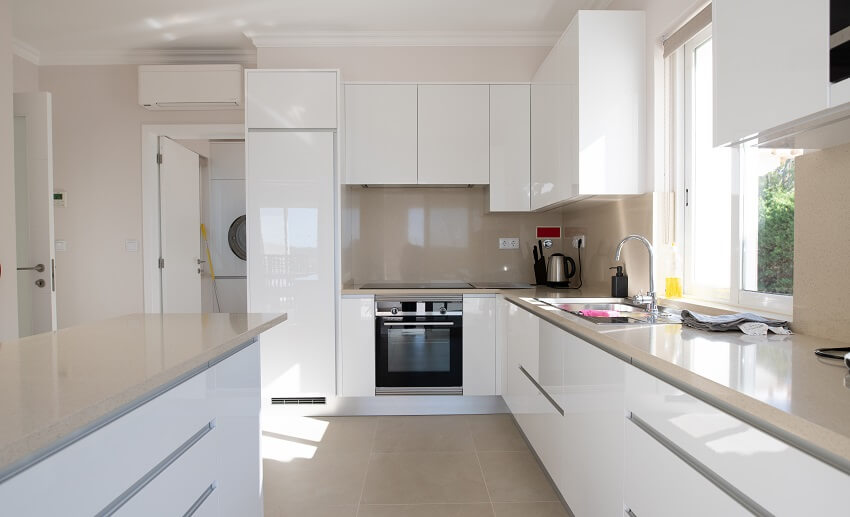 Modern kitchen with white cabinets, and beige stone countertop and ceramic tiled floor