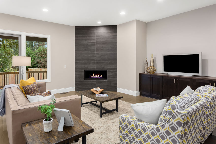 Modern living room with a fireplace, glass window, couch, sofa chairs, rug, carpet, television, and recessed lighting