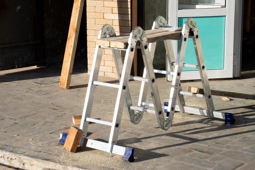 Multi purpose ladder with a slab of wood on it