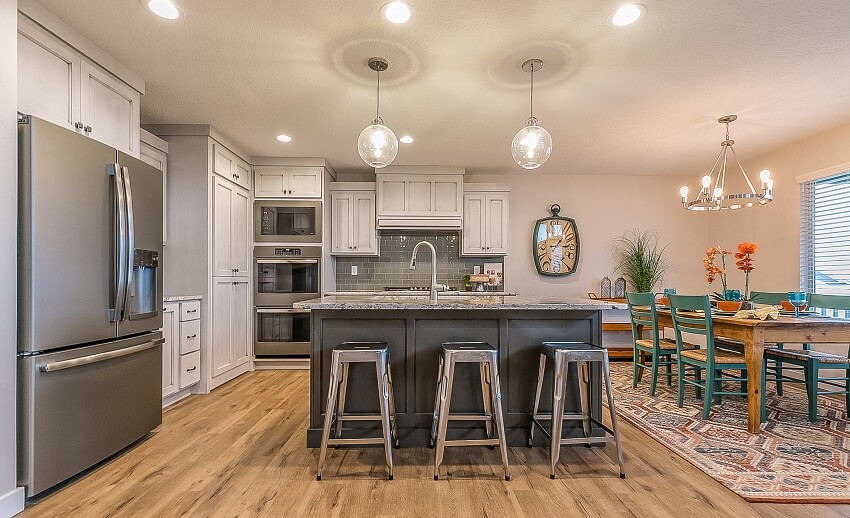 Open dining and kitchen with subway tile backsplash, white cabinets, and blue dining chairs