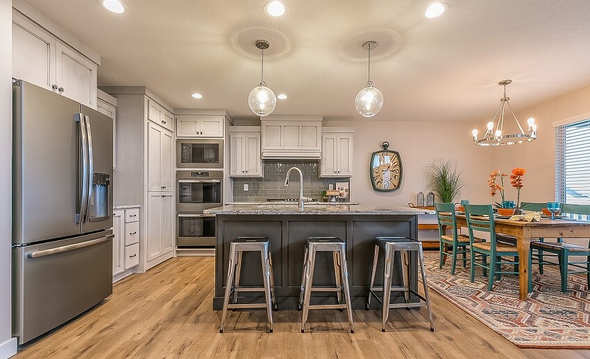 Open dining and kitchen with subway tile, white cabinets, and blue dining chairs