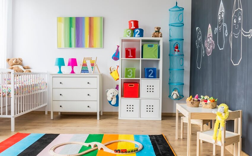 Organized playroom with white wooden furniture drawing wall and a blue hanging stuff toy storage