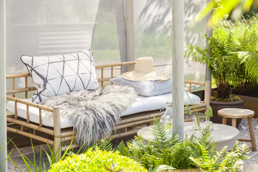 Outdoor area with bamboo daybed, cushion, stool, and plants