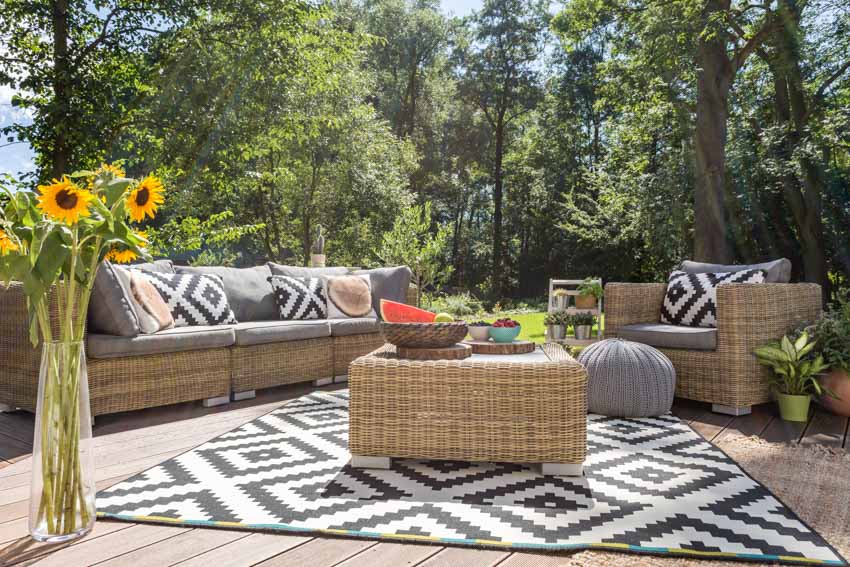Deck with rug, wicker seating, sofa, cushions, and pillows