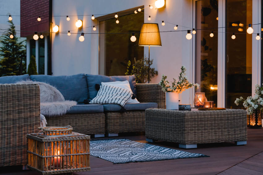 Outdoor deck with lighting fixtures, wicker furniture, and pillows
