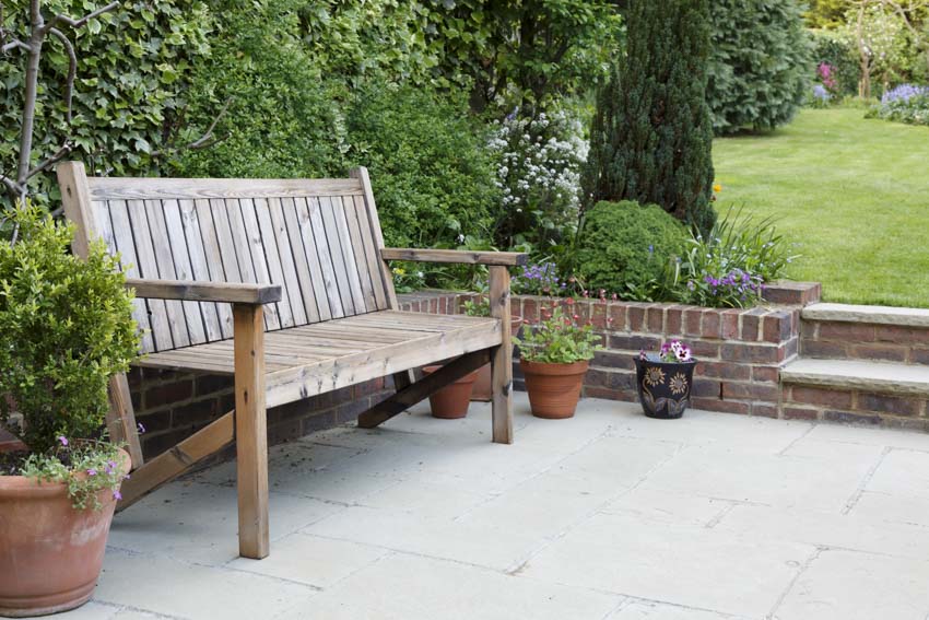 Outdoor garden area with wooden bench, and potted plants