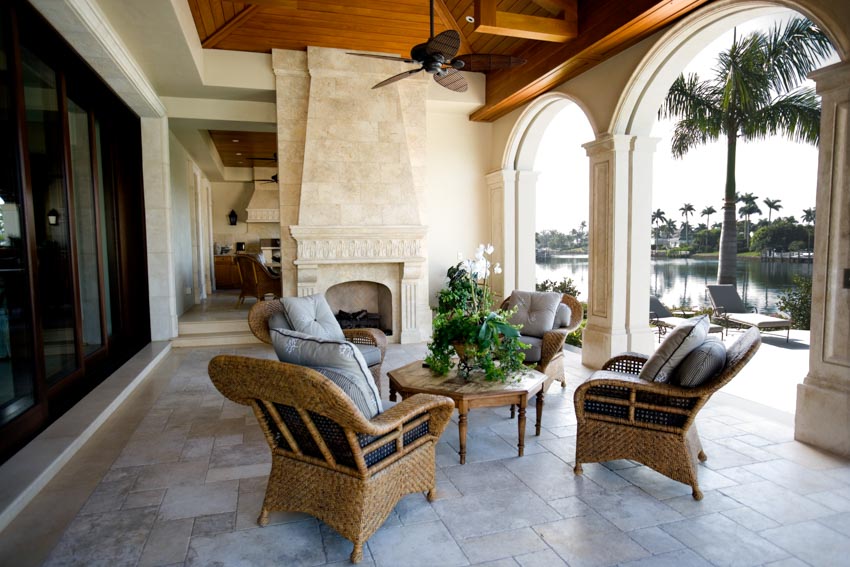 Outdoor space with limestone fireplace, chairs, small table, and tile patio
