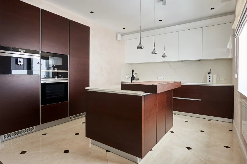 Painted laminate cabinets, island, tile floor, built-in ovens, and pendant lights in a modern kitchen