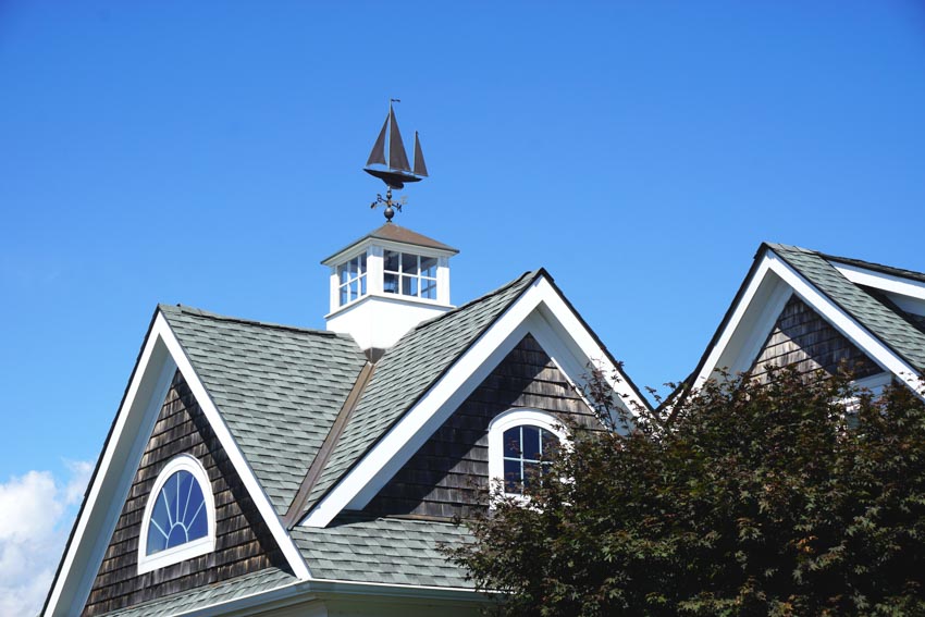 Pitched gray roof with a cupola and weathervane on top of it