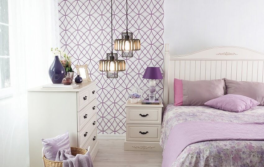 Purple themed bedroom with patterned wallpaper, pendant lights, and large cozy bed