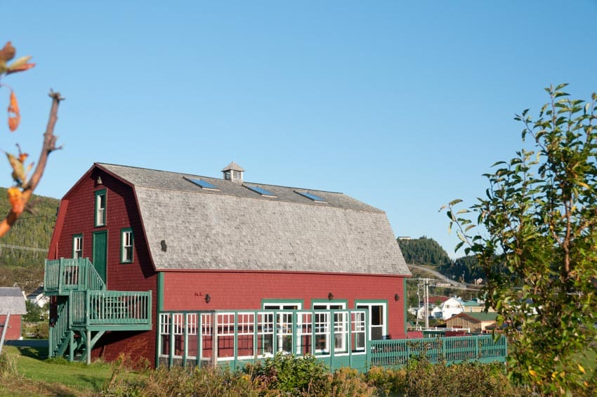 Red barndominium with green stair railings, cupola, and pitched roof