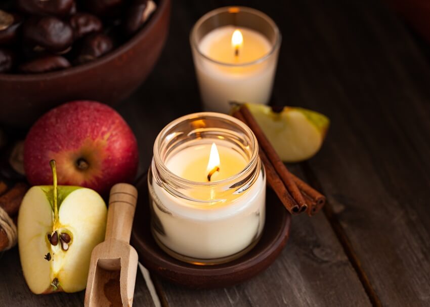 Scented candles with apple, cinnamon and chestnut in a dark wooden background