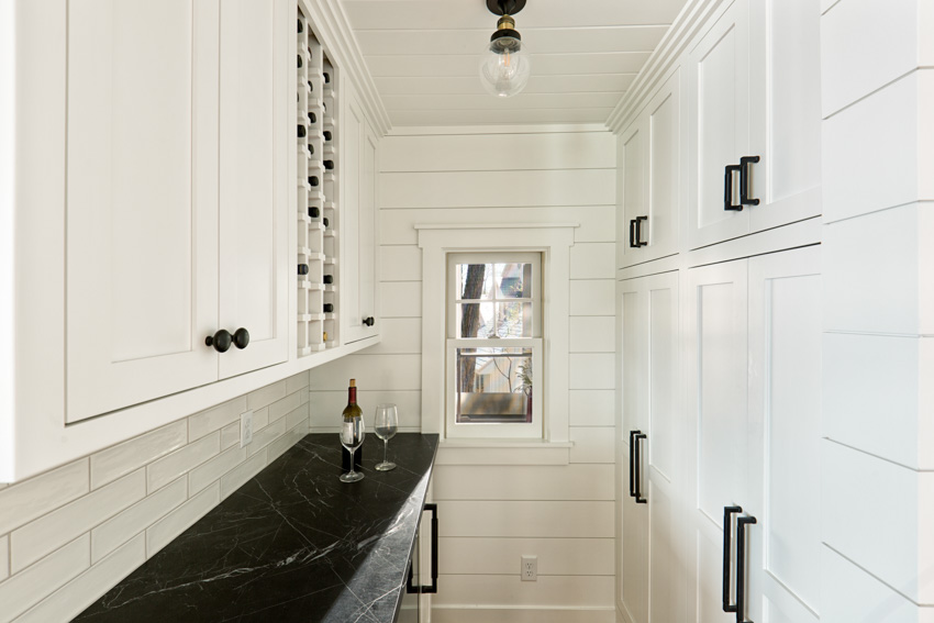 Small butler's pantry with tile backsplash countertop, white cabinets, and ceiling lights