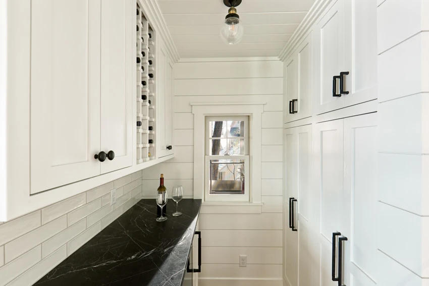 Small butler's pantry with tile backsplash countertop, white cabinets, and ceiling lights