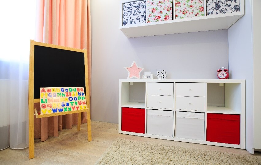 Small playroom with white cubby storage wood floors carpet and a small black board