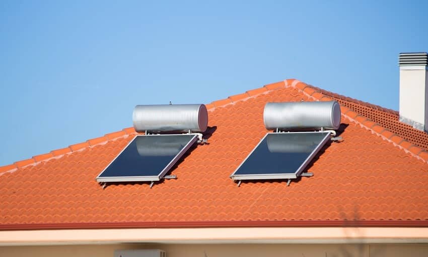 Solar heater panels on red tile roof with chimney
