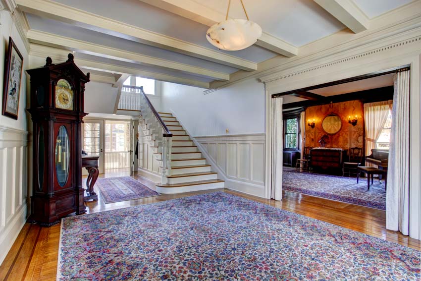 Spacious hallway with carpet, staircase, and clock
