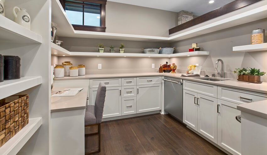 Spacious walk-in butlers pantry with white open shelves and cabinets, dishwasher, and a built-in desk