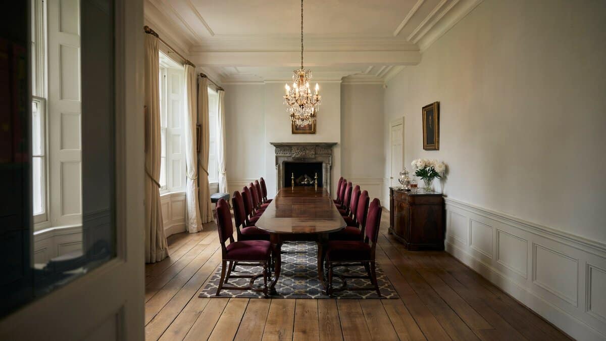 Traditional dining table with burgundy chairs, fireplace, wainscoting, and hardwood flooring