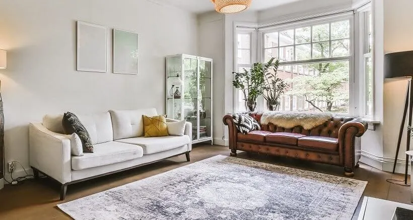 Two different sofas a carpet and a rattan pendant light in an apartment living room