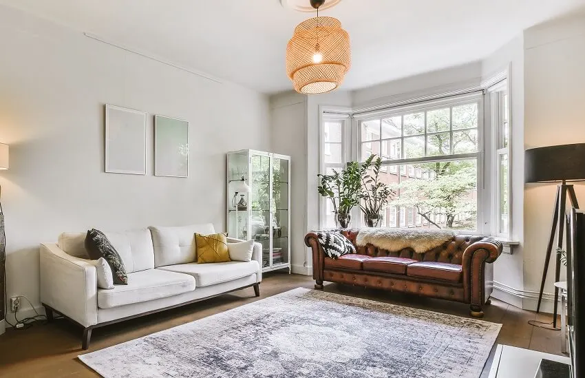 Two different sofas, a carpet, and a rattan pendant light in an apartment living room