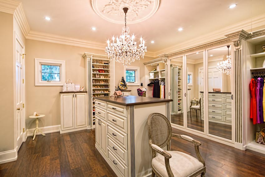 Walk-in closet with center island, white drawers, wood floor, chair, and chandelier