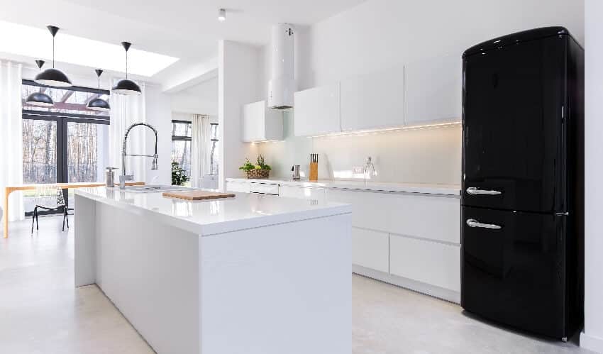 White and bright kitchen with vinyl flooring, pendant lights, black appliance, and island with sink