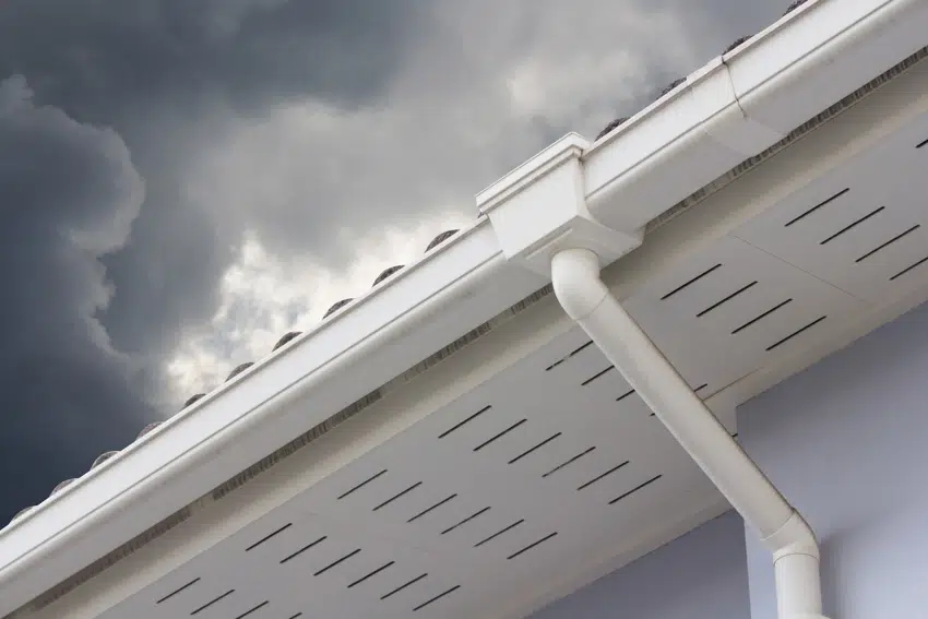 White gutter with guard installed at the bottom of a roof