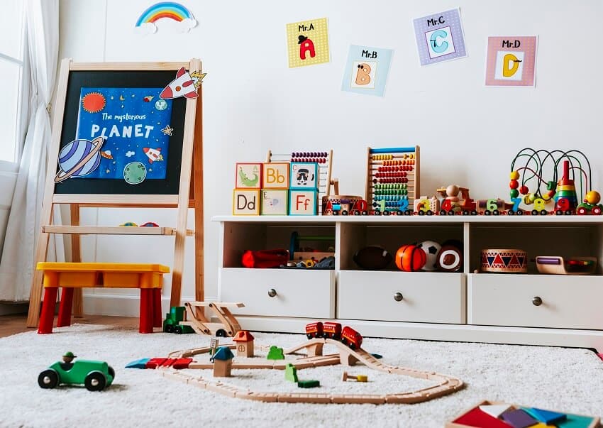 White playroom with toys on a carpet artwork letters on wall and a wooden toy storage